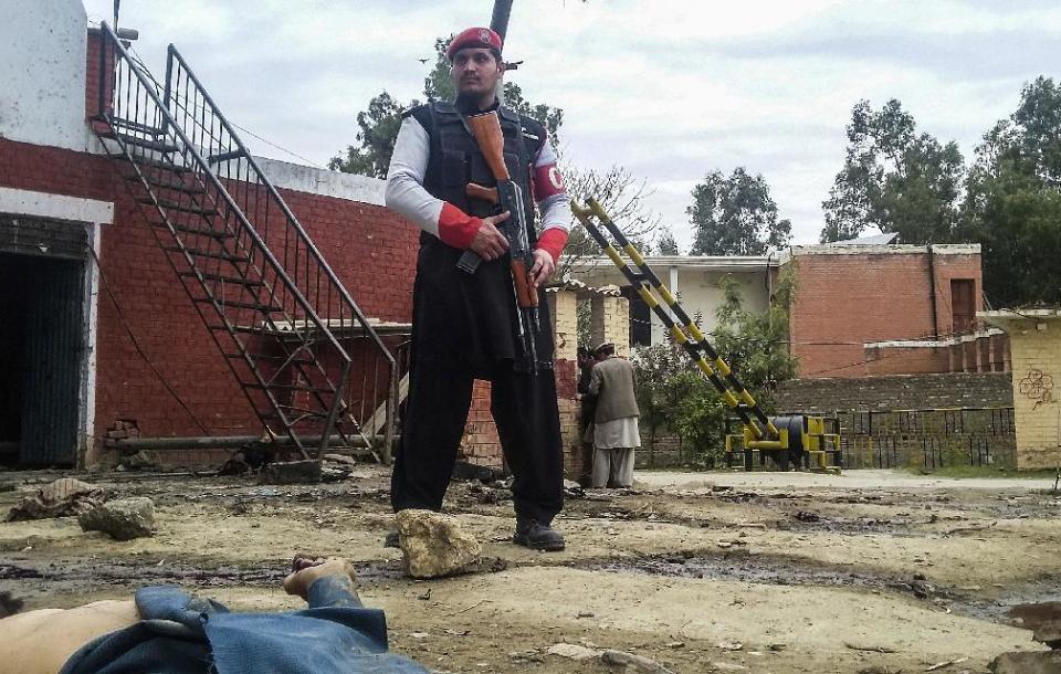 A Pakistani security officer stands alert at the site of a bombing in Ghalanai in the Pakistan's tribal region of Mohmand, Wednesday, Feb. 15, 2017. A Taliban suicide bombing targeted the administrative headquarters of a tribal region in northwestern Pakistan on Wednesday, killing scores of policemen and two passers-by, according to officials. (AP Photo/Alamgir Khan)