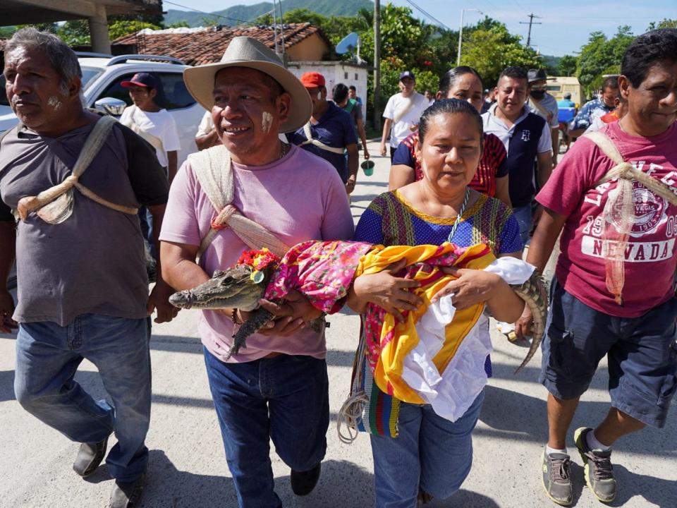 People carry a seven-year-old alligator before a traditional ritual marriage, likely dates back centuries to pre-Hispanic times, between the San Pedro Huamelula Mayor Victor Hugo Sosa and the reptile that depicts a princess, as a prayer to plead for nature's bounty, in San Pedro Huamelula, in Oaxaca state, Mexico June 30, 2022. REUTERS/Jose de Jesus Cortes