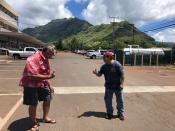 In this Wednesday, April 1, 2020 photo Glen Kila, left, and Brad Suzuki, right, flash the Hawaii "shaka" signs with their hands and give slight bows, demonstrating how they greet people using social distancing to curb the spread of coronavirus in Waianae, Hawaii. People in Hawaii are changing how they express aloha in the time of coronavirus. Residents say social distancing is necessary, even though it's the antithesis of tradition in the state, where people greet each other with hugs, kisses and lei, and families are close-knit. (AP Photo/Jennifer Sinco Kelleher).