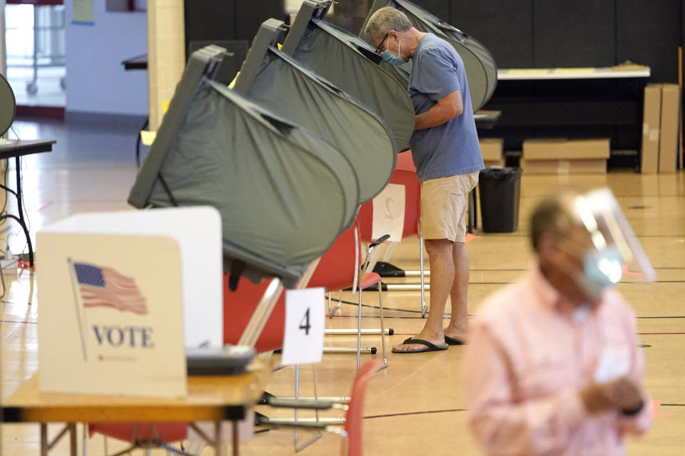 A man wears a mask while voting, Monday, June 29, 2020, in Houston. Early voting for the Texas primary runoffs began Monday. (AP Photo/David J. Phillip)