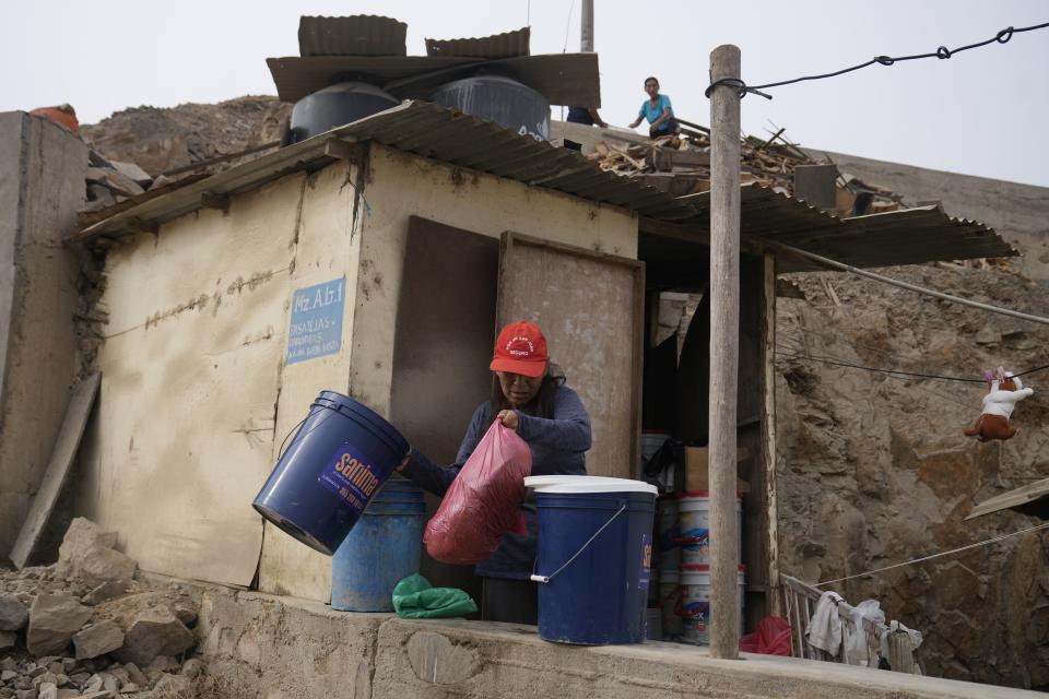 Dolores Umeres reemplaza el aserrín que utiliza para su retrete seco, como parte del programa de saneamiento alternativo, en el barrio de Pamplona Alta de Lima, Perú, el miércoles 20 de marzo de 2024. El servicio incluye el reparto de aserrín, la instalación del baño seco y el traslado de los desechos hacia un contenedor que semanalmente lleva 40 toneladas a un relleno sanitario. (AP Foto/Martín Mejía)