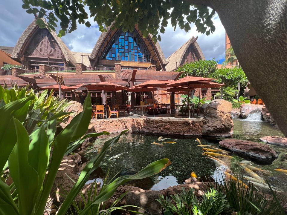 A restaurant patio with chairs and umbrellas overlooking a koi pond.