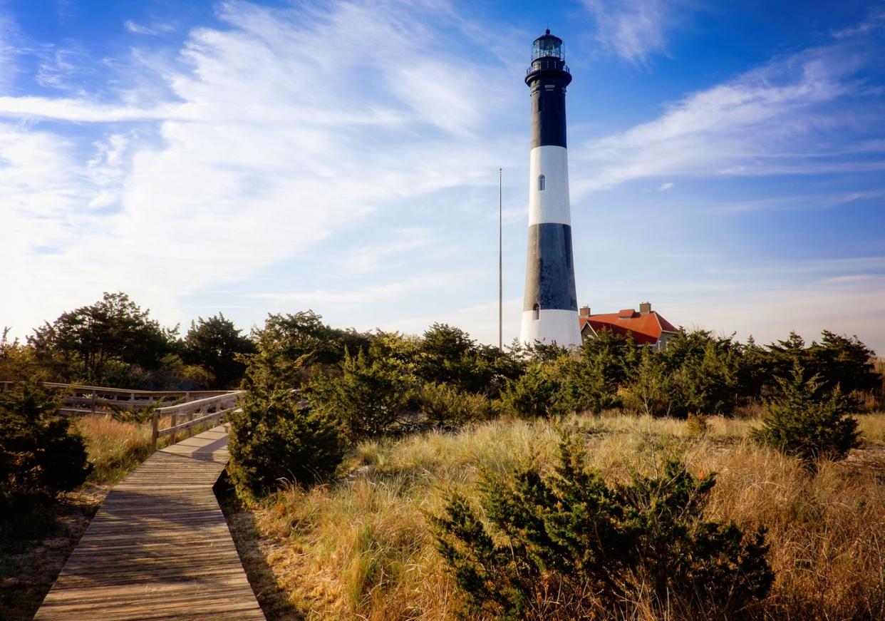 striped back and white lighthouse with a boardwalk heading up to it