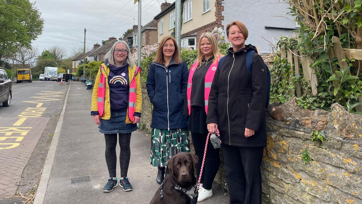 Four organisers and a dog underneath a pedestrian and cycle sign