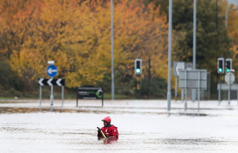 An emergency service worker stands at a flooded road in central Rotherham, near Sheffield