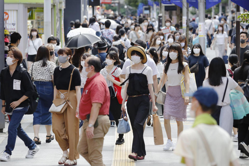 People make their way on a street in Tokyo Sunday, Aug. 2, 2020. Confirmed coronavirus cases are hovering at near record levels in Japan, raising worries the pandemic may be growing more difficult to control. The Tokyo government reported more than 290 new cases Sunday, about half in their 20s. (Kyodo News via AP)