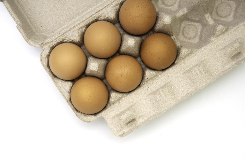 Top view of raw chicken eggs in egg box on on white background.