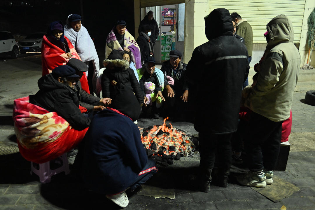 甘肅地震，當地低溫影響救災，災民逃難後，圍在火爐旁取暖。(圖片來源：CNS/AFP/ Getty Images)