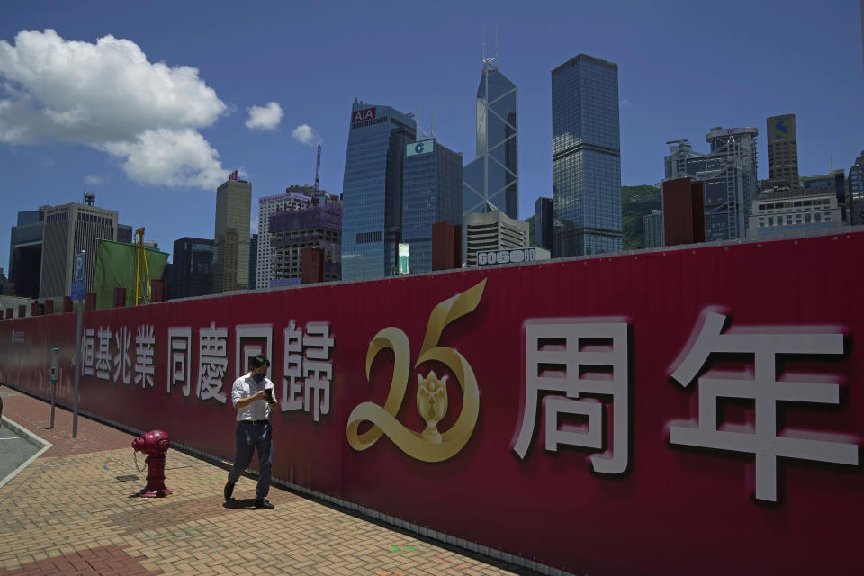 A man walks past a banner to celebrate the 25th anniversary of Hong Kong handover to China, in Hong Kong, Thursday, June 23, 2022. As the former British colony marks the 25th anniversary of its return to China, reeling from pandemic curbs that devastated business and a crackdown on its pro-democracy movement, Hong Kong leaders say it is time to transform again and become a tech center that relies more on ties with nearby Chinese factory cities than on global trade. (AP Photo/Kin Cheung)