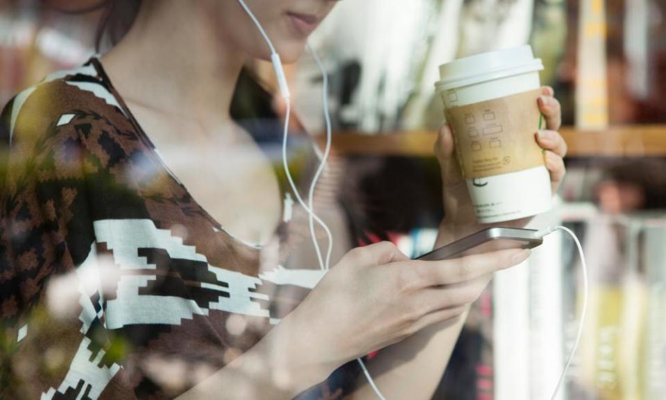 woman listening to smartphone in coffee shop