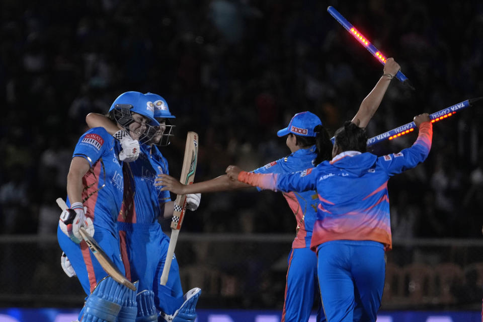 Mumbai Indians Natalie Sciver, left, celebrate with teammates their win in the Women's Premier League Twenty20 cricket final match against Delhi Captials in Mumbai, India, Sunday, March 26, 2023. (AP Photo/Rajanish Kakade)