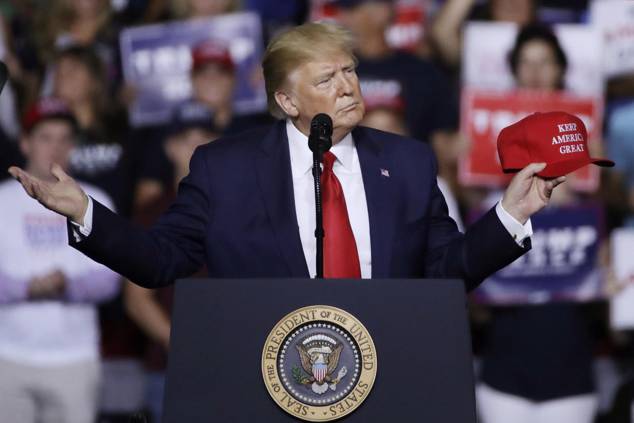 President Trump holds a "Keep America Great" hat as he speaks at a campaign rally in Manchester, N.H., on Thursday. (AP Photo/Elise Amendola)