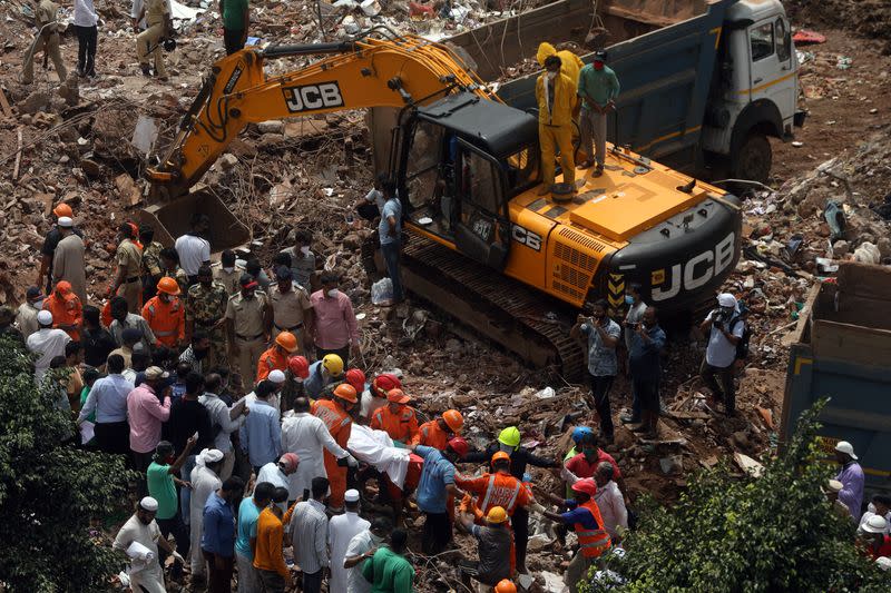 Rescue workers search for survivors in the debris after a five-story building collapsed in Mahad