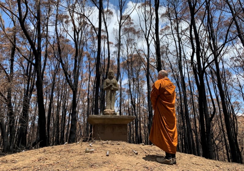 The Abbot of Sunnataram Forest Monastery, Phra Mana, 56, prays in front of a Buddhist statue near a burnt forest in Bundanoon, Australia