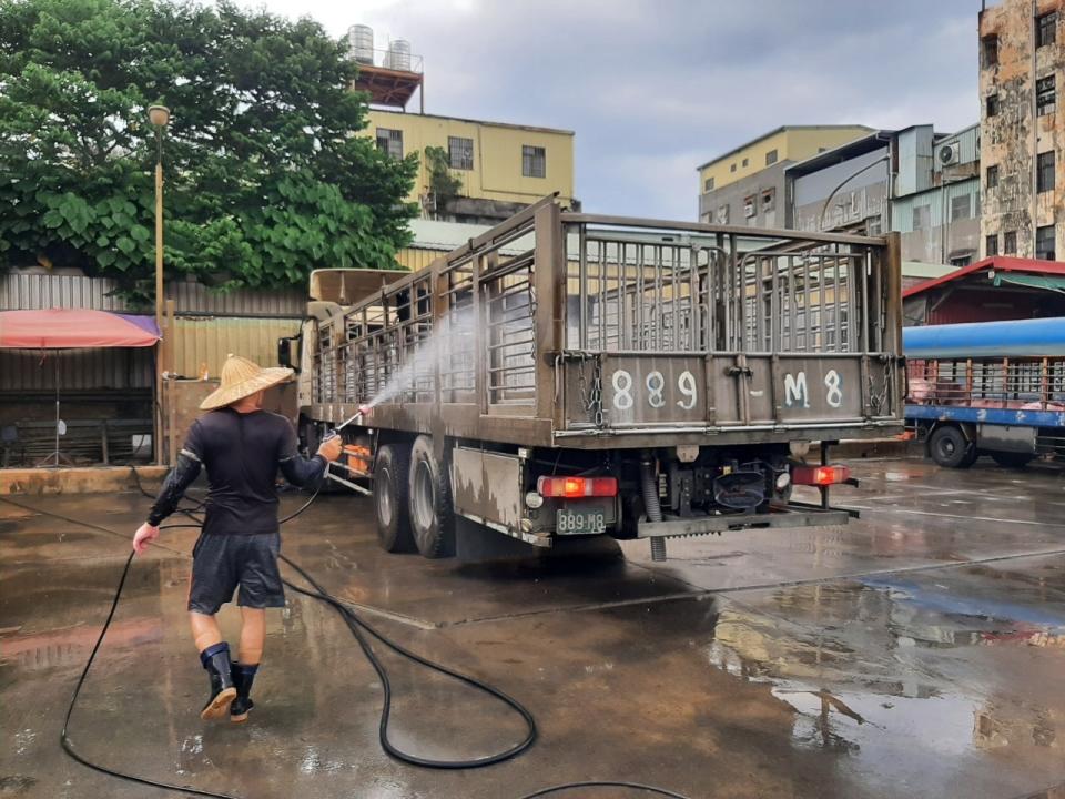 運豬車司機進行運輸車輛裝載箱籠平台消毒作業。   圖：新北市動保處提供