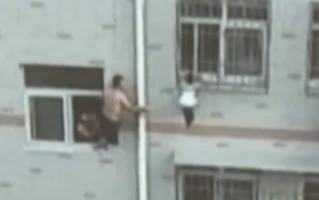 Wang Baocheng used a mop to support a young girl who became stuck between the windows bars of her apartment in Weifang City. Source: CCTV.
