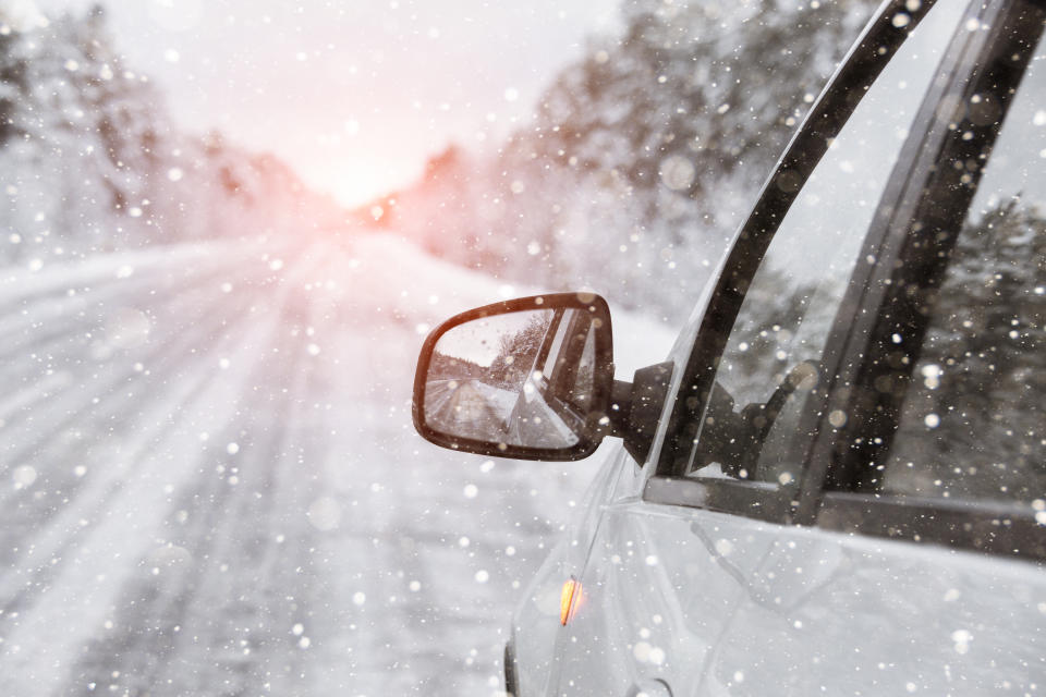 The winter road is reflected in the car's rear-view mirror