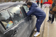 Michigan running back Blake Corum delivers to a car a tray containing a turkey, vegetables and other items during a giveaway event outside a school in Ypsilanti, Mich., on Sunday, Nov. 20, 2022. Corum took part in the charitable effort a day after hurting his knee and less than a week before his third-ranked Wolverines play No. 2 Ohio State. (AP Photo/Mike Householder)