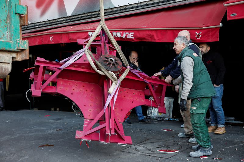 The broken sails of the landmark red windmill atop the Moulin Rouge, Paris' most famous cabaret club, are taken away after they fell off during the night in Paris