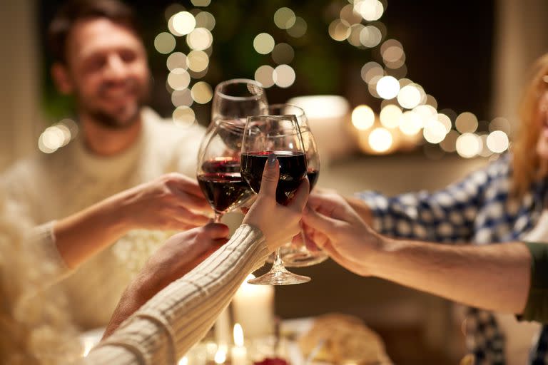 holidays, celebration and people concept - happy friends having christmas dinner at home drinking non-alcoholic red wine