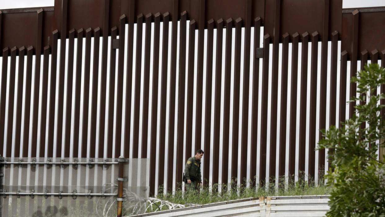 A Border Patrol agent walks along a border wall separating Tijuana, Mexico, from San Diego.