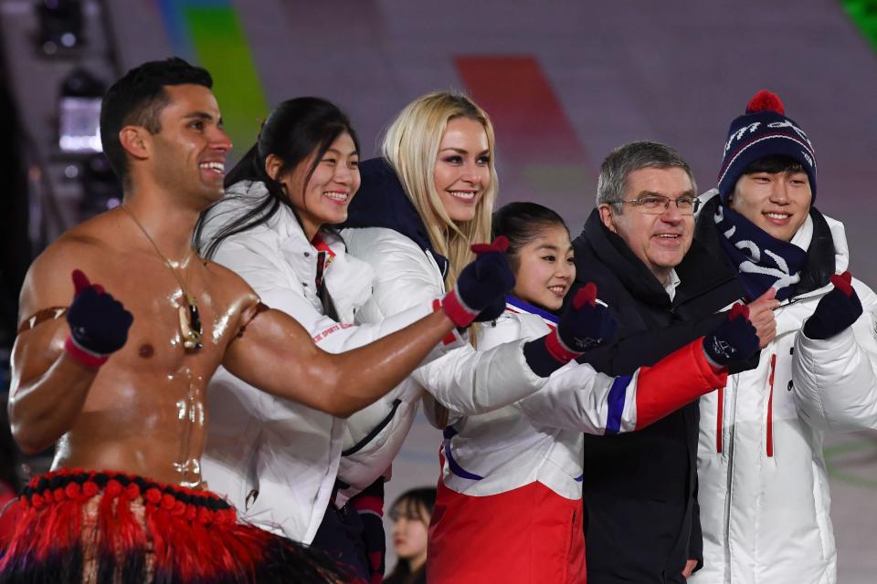 Taufatofua joined China's Liu Jiayu, USA's Lindsey Vonn, North Korea's Ryom Tae-ok, International Olympic Committee President Thomas Bach and South Korea's Yun Sungbin to make heart shapes with their fingers during the closing ceremony of the Winter Olympics. (Photo: JONATHAN NACKSTRAND via Getty Images)