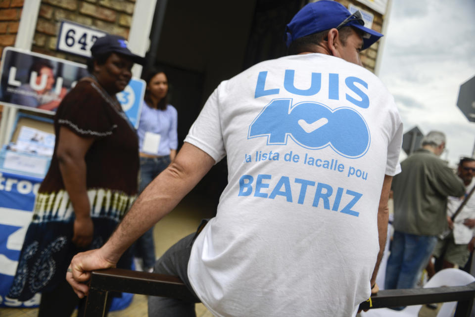 A supporters of Luis Lacalle, presidential candidate from the National Party, sits outside a polling station in Canelones, Uruguay, Sunday, Oct. 27, 2019. Fifteen years of leftist rule hangs in the balance as Uruguay faces a tight presidential election that is likely to head to a runoff vote.(AP Photo/Santiago Mazzarovich)