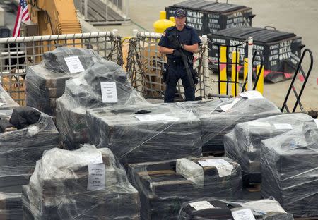 An armed crew member of the U.S. Coast Guard Cutter Stratton keeps watch as more than 66,000 pounds of cocaine worth $1.01 billion wholesale that was seized in the Eastern Pacific Ocean is unloaded upon arrival in San Diego, California August 10, 2015. REUTERS/Mike Blake