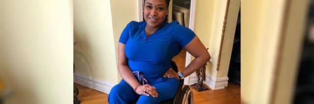 Andrea Dalzell in her blue nurse&#039;s uniform, sitting in her wheelchair.