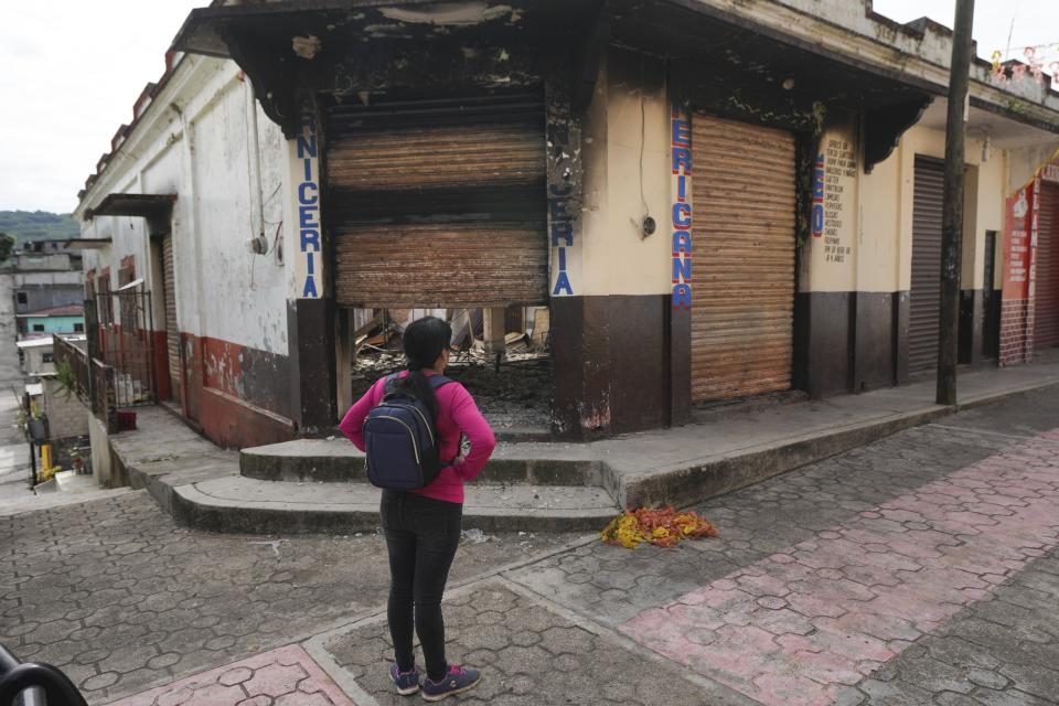 Una vecina observa los restos quemados de un edificio incendiado en Tila, en el estado de Chiapas, México, el martes 18 de junio de 2024. La población se está marchando de la localidad debido a la violencia relacionada con el crimen organizado. (AP Foto/Fernando Llano)