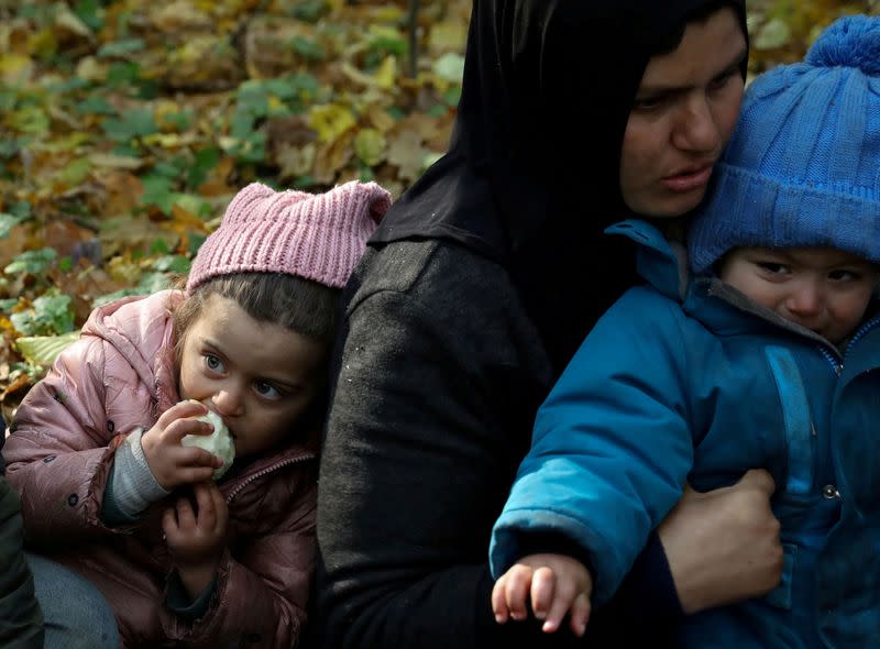 FILE PHOTO: An Iraqi migrant woman with children sits on the ground as they are surrounded by border guards and police officers after they crossed the Belarusian-Polish border during the ongoing migrant crisis, in Hajnowka