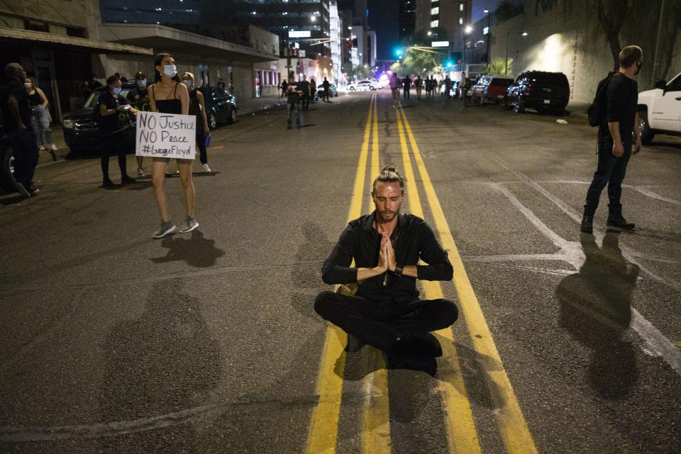 Jesse Fairchild mediates near police officers in riot gear in downtown Phoenix on May 30, 2020.