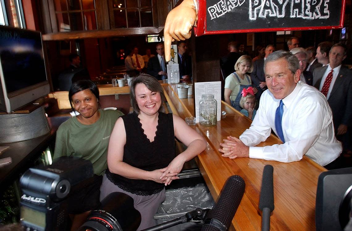 President George W. Bush stopped by Rockaway Athletic Club, a popular local restaurant in Columbia, after he spoke before a joint session of the South Carolina General Assembly in Columbia, S.C. Monday, April 18, 2005. Here, he poses for the media with waitress Charlynna Foster (L) and bartender Catherine Bailey. He greeted some of the customers while he was there and ordered a pimento cheeseburger, a specialty of the restaurant.