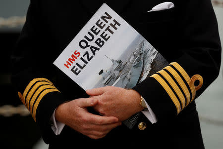 A Naval officer listens to speeches after the arrival of the Royal Navy's new aircraft carrier HMS Queen Elizabeth in Portsmouth, Britain August 16, 2017. REUTERS/Peter Nicholls