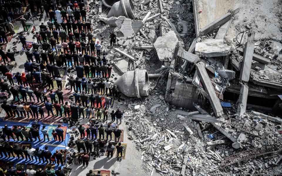 Palestinians perform Friday prayers among the rubble of the Al-Farooq Mosque