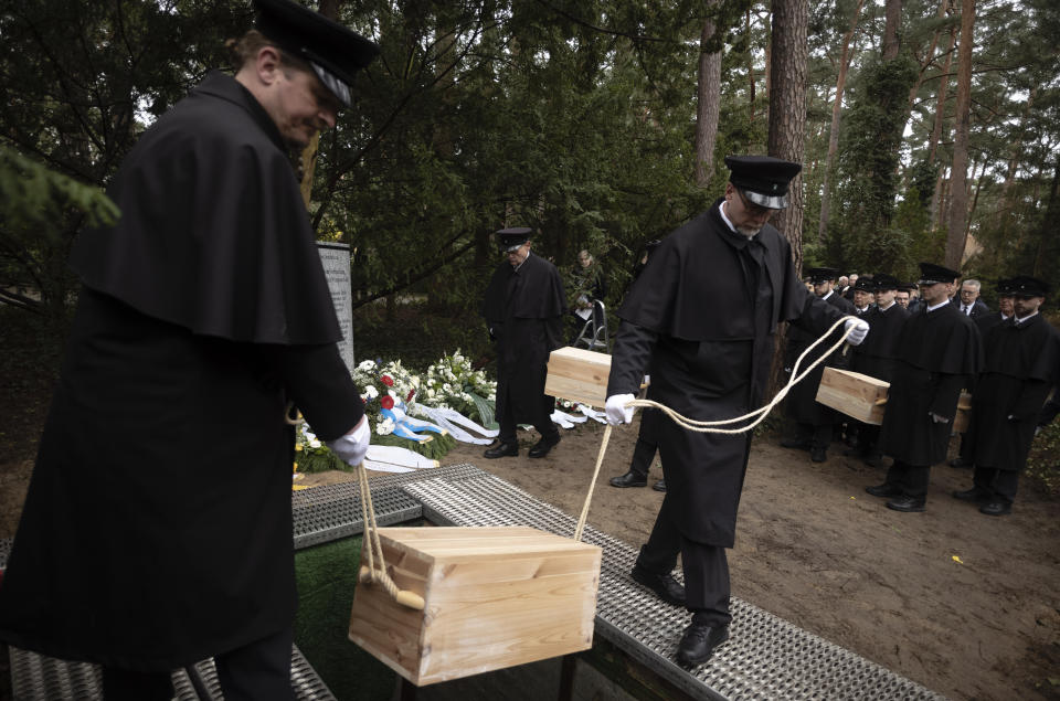 Caskets containing bones found on the grounds of the Freie Universitat, Free University are lowered into the ground for burial, at the Waldfriedhof in Berlin, Germany, Thursday, March 23, 2023. Thousands of bone fragments found in the grounds of a Berlin university where an institute for anthropology and eugenics was once located, which may include the remains of victims of Nazi crimes, were buried on Thursday. (AP Photo/Markus Schreiber)