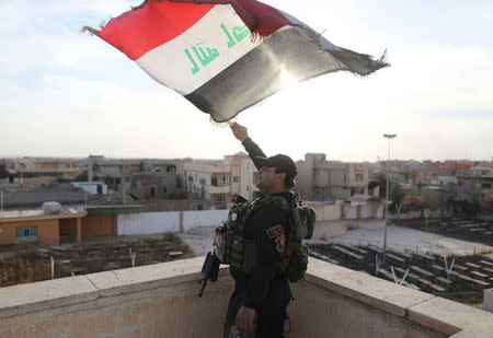 An Iraqi special forces soldiers waves an Iraqi flag from top of a church damaged by Islamic States fighters in Bartella, east of Mosul, Iraq, October 21. 2016. REUTERS/Goran Tomasevic