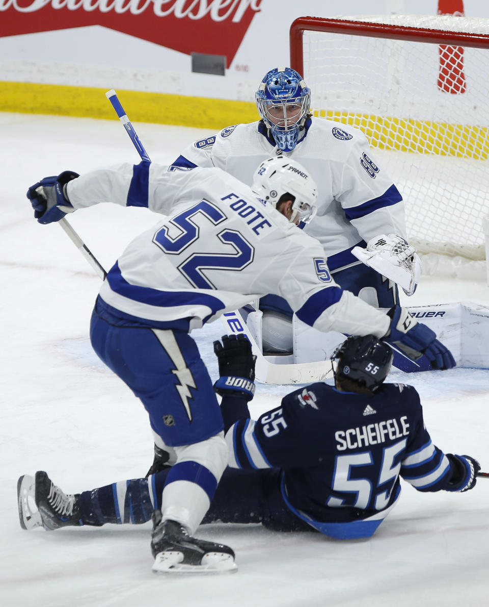 Winnipeg Jets' Mark Scheifele (55) is hauled down by Tampa Bay Lightning's Cal Foote (52) in front of Lightning goaltender Andrei Vasilevskiy (88) during second-period NHL hockey game action in Winnipeg, Manitoba, Friday, Jan. 6, 2023. (John Woods/The Canadian Press via AP)