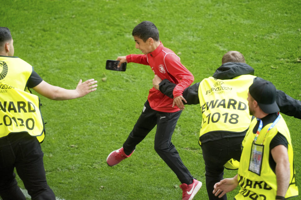 Stewards catch a young pitch invader who ran to Portugal's Cristiano Ronaldo during a Group F match between Turkey and Portugal at the Euro 2024 soccer tournament in Dortmund, Germany, Saturday, June 22, 2024. (AP Photo/Michael Probst)