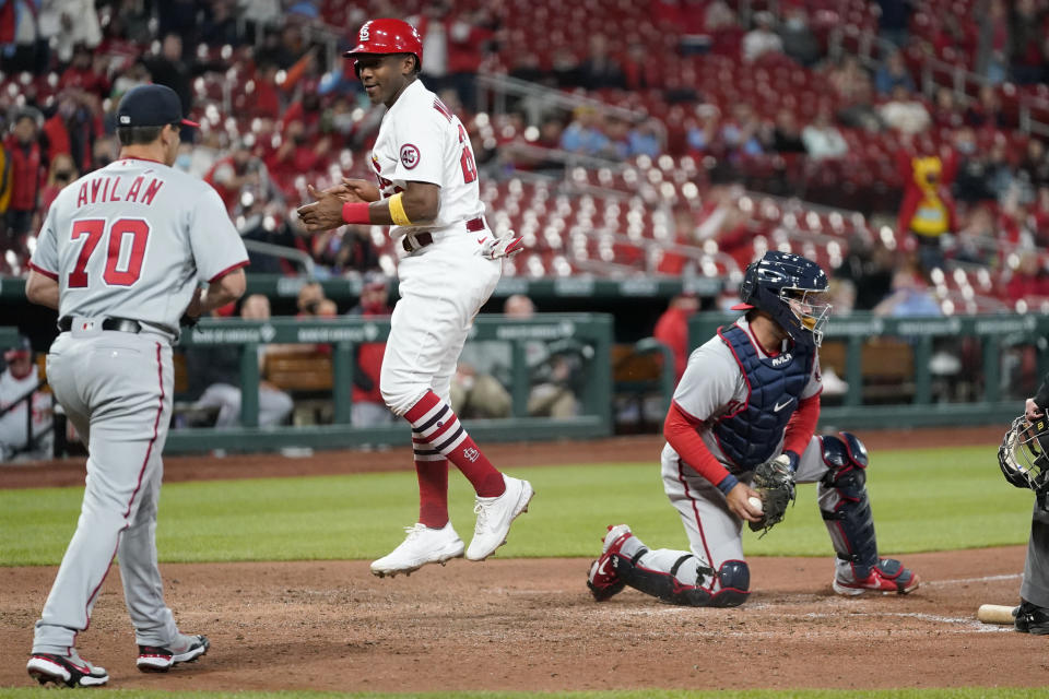 St. Louis Cardinals' Justin Williams, center, celebrates after scoring past Washington Nationals catcher Alex Avila, right, as Nationals pitcher Luis Avilan (70) watch during the fifth inning of a baseball game Tuesday, April 13, 2021, in St. Louis. (AP Photo/Jeff Roberson)