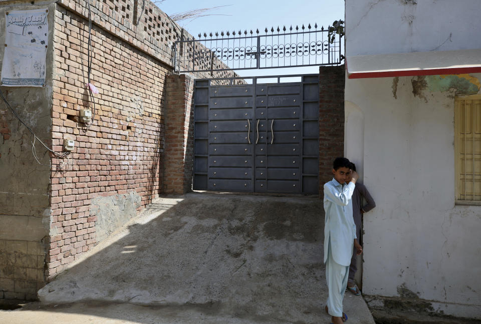 Youngsters stand outside the family house of Ali Hassan, who allegedly attacked two people with a meat cleaver in Paris last month, in Kotli Qazi, Pakistan, Saturday, Oct. 3, 2020. Before the attack, Hassan proclaimed in a video that he was seeking vengeance after the French satirical newspaper Charlie Hebdo republished caricatures of Islam’s Prophet Muhammad. In his remote Pakistani village, where religious fervor runs high, they call him a hero. (AP Photo/Anjum Naveed)