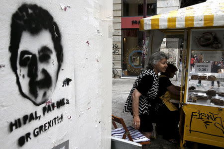 A woman takes a seat next to a stencil in Athens June 8, 2015. REUTERS/Alkis Konstantinidis