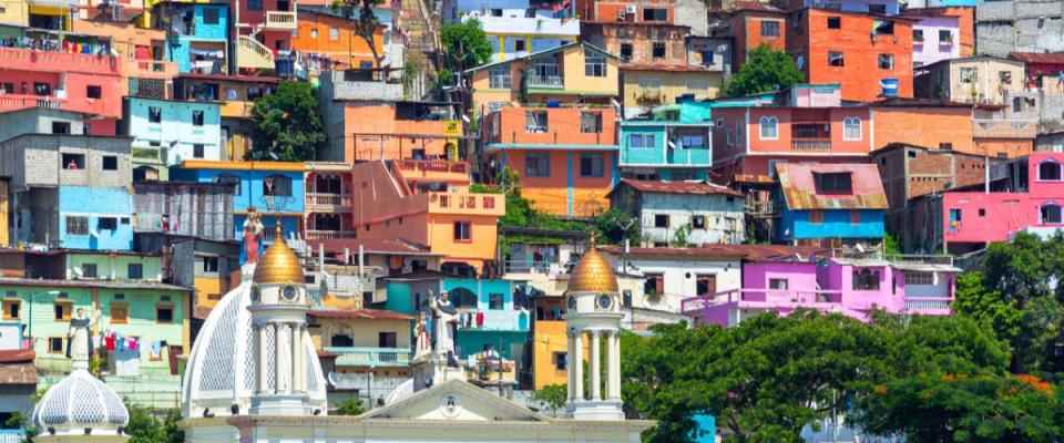 White church with a colorful slum on a hill rising above it in Guayaquil, Ecuador