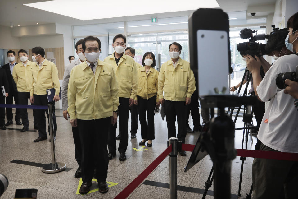 South Korean Prime Minister Chung Sye-kyun, fifth from left, stands to have his body temperature checked upon his arrival at a private educational academy to check the prevention measures of the new coronavirus in Seoul, South Korea, Thursday, July 2, 2020. South Korea reported dozens of new cases as the virus continues to spread beyond the capital area and reach cities like Gwangju, which has shut schools and tightened social restrictions after dozens were found infected this week. (AP Photo/Ahn Young-joon)