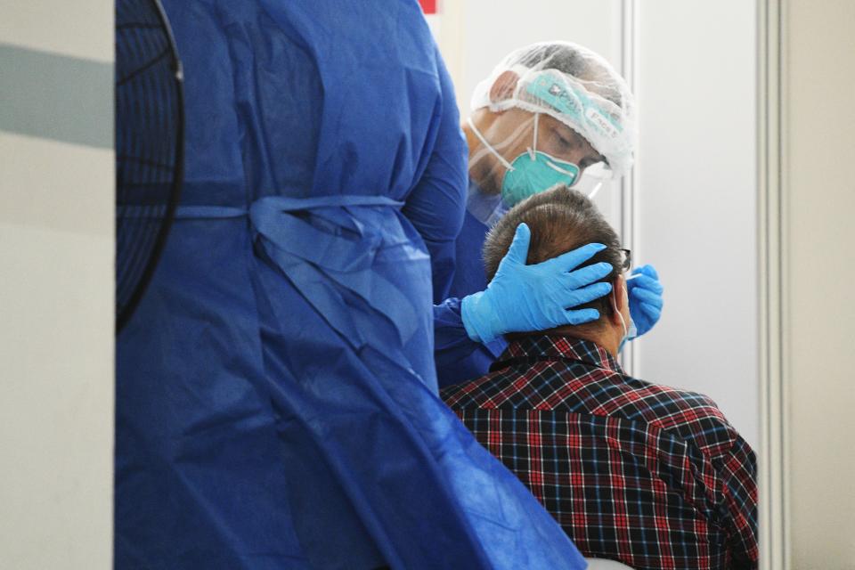 A resident undergoes mandatory COVID-19 swab test at a temporary swab center set up at a void deck of a housing block, after cases of residents found infected with COVID-19 in the block in Singapore's Hougang area on May 21, 2021. (Photo by Then Chih Wey/Xinhua via Getty Images)