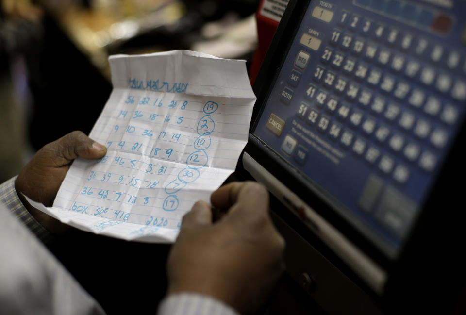 Convenience store clerk Woody Amlak inserts customer Javon Lee's Powerball numbers into a machine in Baltimore, Wednesday, Nov. 28, 2012. Lee, a manager of a local McDonald's restaurant who was playing Powerball for the first time, picked the numbers using a combination of family members' birthdays and addresses. (AP Photo/Patrick Semansky)