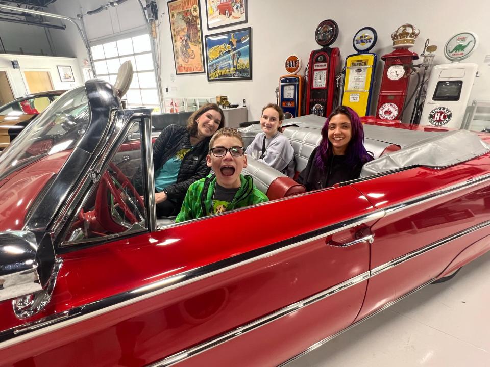 A Camp Sunshine family from Denver, Colorado enjoyed a stop at the Maine Classic Car Museum for a VIP Tour of classic cars after their week at camp. Clockwise from the top, Andrea Reitzel, daughter Millie, 16, family companion, Agustina Bossi of Argentina, and son Alexander, 13, who is behind the wheel of a rare 1960 Edsel Ranger convertible.