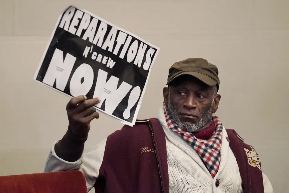 FILE - Morris Griffin holds up a sign during a meeting by the Task Force to Study and Develop Reparation Proposals for African Americans in Oakland, Calif., Dec. 14, 2022. (AP Photo/Jeff Chiu, File)