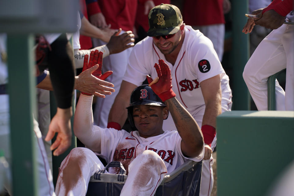 Boston Red Sox's Rafael Devers gets a ride in the dugout after hitting a home run in the third inning in a baseball game against the Seattle Mariners, Saturday, May 21, 2022, in Boston. (AP Photo/Robert F. Bukaty)