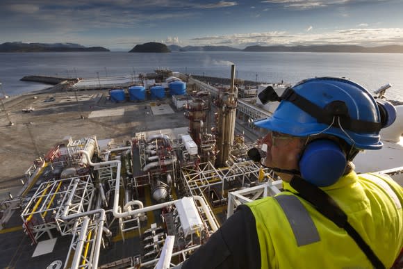 A man looking down from a platform over an oil processing facility